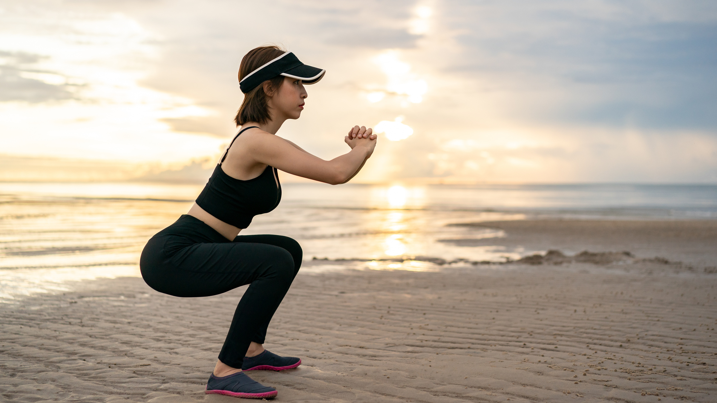 Woman Doing Squat Exercises on the Beach with Sunrise